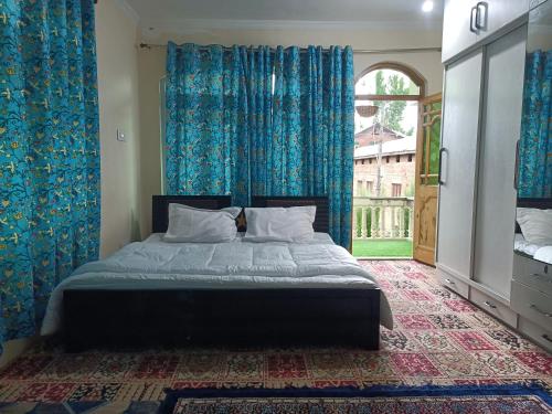 1 dormitorio con 1 cama con cortinas azules y ventana en Coachman HomeStay, en Srinagar