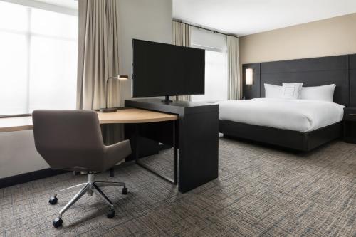 a hotel room with a bed and a desk with a computer at Residence Inn Long Island Garden City in Garden City