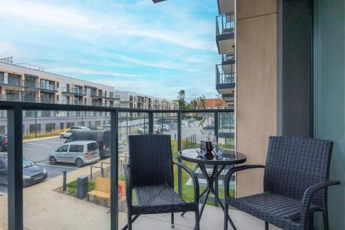 a balcony with two chairs and a table with a view of a street at Apartment Starowiejska with Balcony & Parking next to Gdańsk Arena Stadium by Renters in Gdańsk