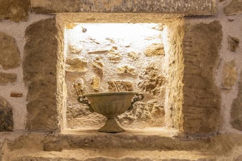 a vase sitting in a window in a stone wall at Arcaloro Resort in SantʼAngelo di Brolo