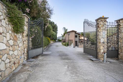 an empty street with a gate and a stone wall at Arcaloro Resort in SantʼAngelo di Brolo