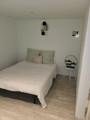 a white bed in a room with a chair at Appartement charmant américain in Hardricourt