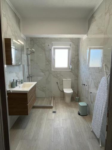a bathroom with a sink and a toilet and a window at Sea Star in Nikiti
