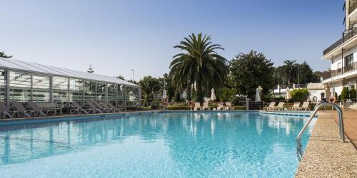 a large swimming pool with chairs and a building at Nuevo Astur Spa in Sanxenxo
