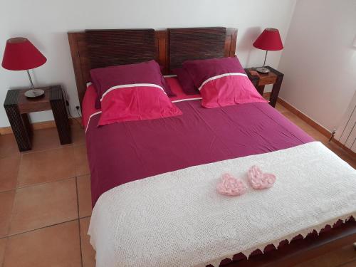 a bedroom with a bed with pink and white sheets and two pink roses at entre mer et campagne in Le Beausset