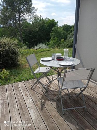 une table et deux chaises assises sur une terrasse dans l'établissement Quietude, à Périgueux