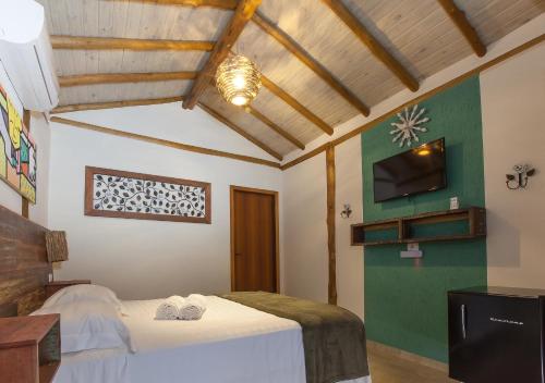 a bedroom with a bed and a flat screen tv at Pousada de Charme Emirados in Ilhabela