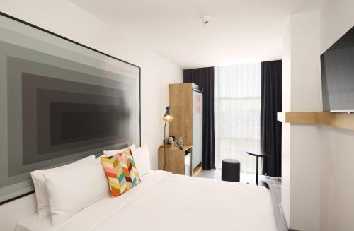 a bedroom with a white bed with a large television at Ibis Istanbul Airport in Istanbul