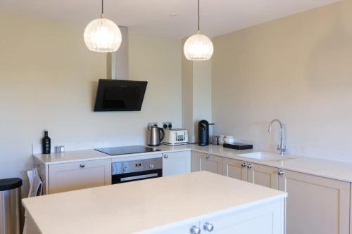 a kitchen with white appliances and two lights at Greentrees Estate - The Chestnut Cottage in Balcombe