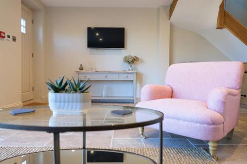 a living room with a pink chair and a glass table at Greentrees Estate - The Chestnut Cottage in Balcombe