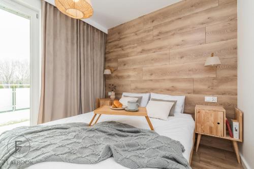a bedroom with a bed and a wooden wall at Flatbook Apartamenty - Sztutowo Baltic Sun -B-I- in Sztutowo