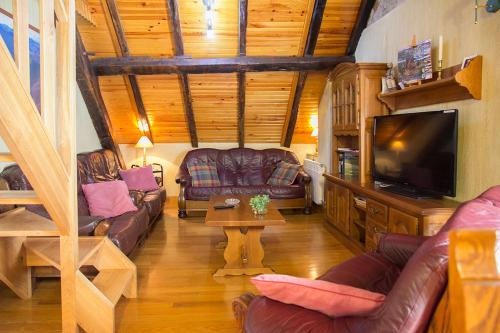 sala de estar con sofás de cuero y TV de pantalla plana en Casa rural Txikirrin II - Selva de Irati, en Villanueva de Aézcoa