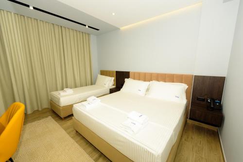 una habitación de hotel con 2 camas y una silla en KAAN Hotel, en Vlorë