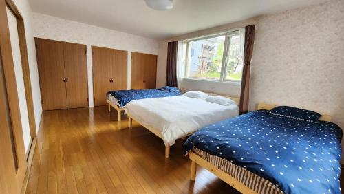 小樽Experience relaxation in Otaru's bungalow的有两张床和一扇窗户的卧室