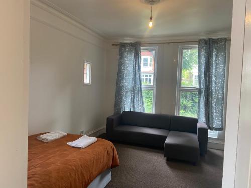 a bedroom with a bed and a couch and a window at Homely 3 Bedroom Ground Floor Flat in London