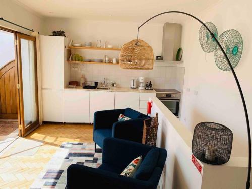 a living room with two blue chairs and a kitchen at CasaWolhão JANEIRO - tour du pêcheur vue mer in Olhão