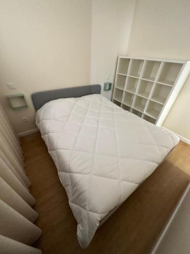 Una cama blanca en una habitación con estantería. en Casa da Poça 2 - Guest House en Braga