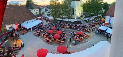 a crowd of people sitting at tables in a street with red umbrellas at Gästezimmer Drexl in Türkenfeld