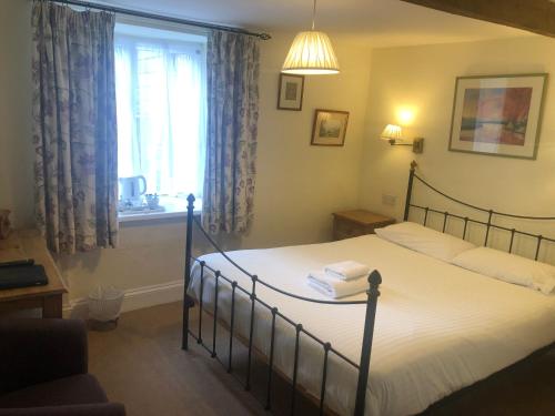 a bedroom with a bed with white sheets and a window at Trehellas House Hotel & Courthouse restaurant in Bodmin