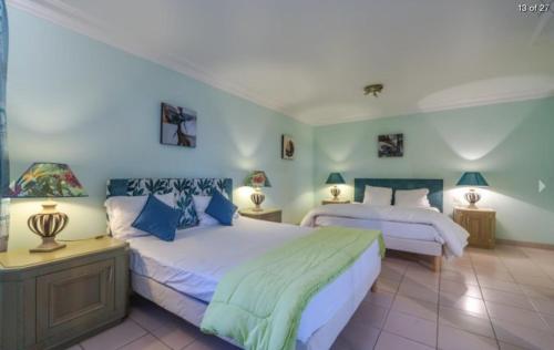 een slaapkamer met 2 bedden en 2 lampen erin bij PROCHE CANNES, SPACIEUX VILLA APPARTEMENT, JARDIN et PISCINE PRIVE in Vallauris