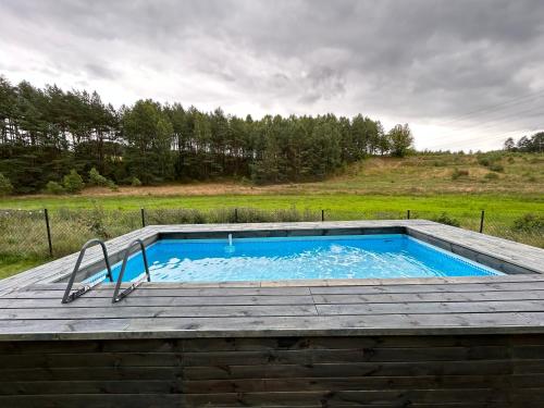 a swimming pool on a wooden deck with at Cosy Cabin - domek na Kaszubach z sauną, balią i basenem in Stara Sikorska Huta