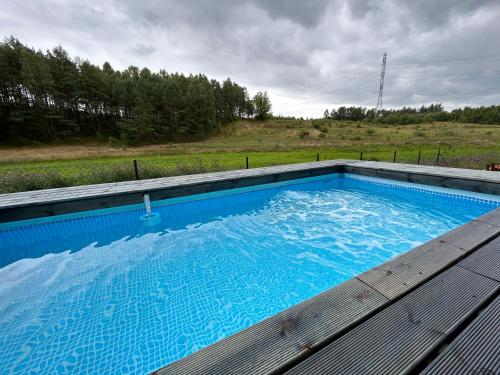 a large blue swimming pool sitting on a wooden deck at Cosy Cabin - domek na Kaszubach z sauną, balią i basenem in Stara Sikorska Huta