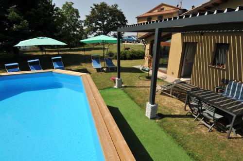a swimming pool with chairs and umbrellas next to a house at Casalotto Francescano in Mengara