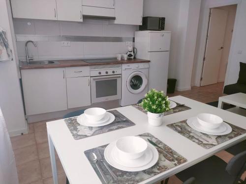 a kitchen with a table with white dishes on it at San Centro Wizink IFEMA Metropolitano Airport Apartments in Madrid