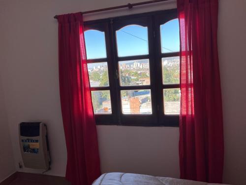 - une fenêtre avec des rideaux rouges dans la chambre dans l'établissement Dptos Los Pajaritos -El Canario-, à San Salvador de Jujuy
