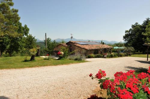 a gravel driveway leading to a house with red flowers at Casalotto Francescano in Mengara