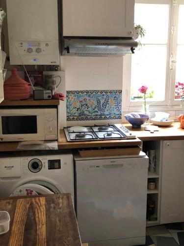 une cuisine avec une cuisinière et une machine à laver dans l'établissement Nice and practical apartment to enjoy Paris close to Montmartre, à Paris
