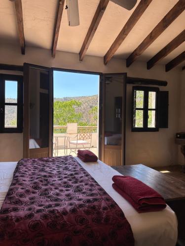 ein Schlafzimmer mit einem großen Bett mit einem großen Fenster in der Unterkunft Cortijo Cuscurro in Ríogordo