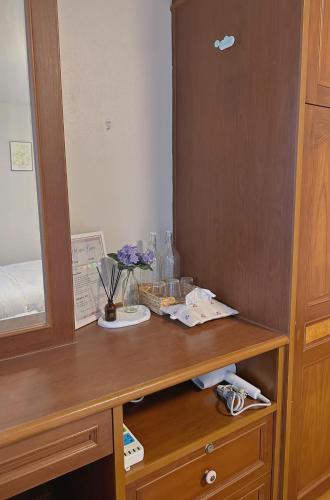 a wooden desk with a mirror and flowers on it at Kong Khong Homestay in Hat Yai