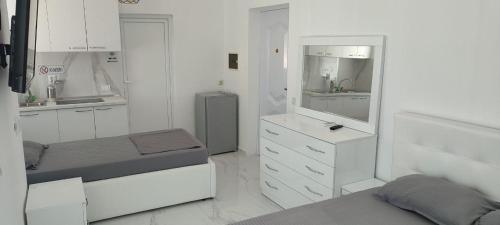 a white bedroom with two beds and a mirror at Golem Apartment in Golem