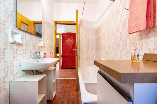 a bathroom with a sink and a red door at Casa nel Borgo Rose in Breguzzo