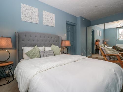 a bedroom with a large white bed with blue walls at The Annexe in Lydney