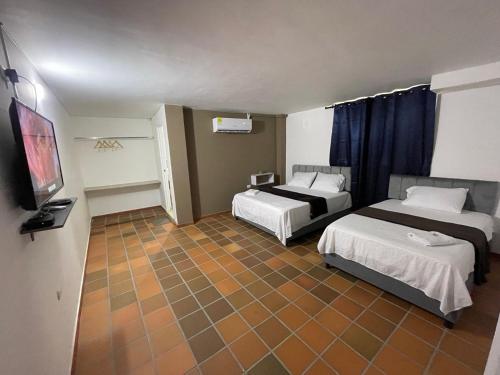 a hotel room with two beds and a flat screen tv at Hotel Valle Central in Valledupar