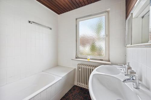 a bathroom with two sinks and a tub and a window at home2stay worker Apartments Nürtingen-Zizishausen Ap1 in Nürtingen