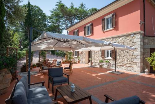 a patio with an umbrella and chairs and a building at Agriturismo Terre della Rinascita in Castelnuovo della Misericordia