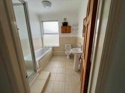 a bathroom with a tub and a toilet and a sink at Guesthouse Kettering City Centre in Kettering