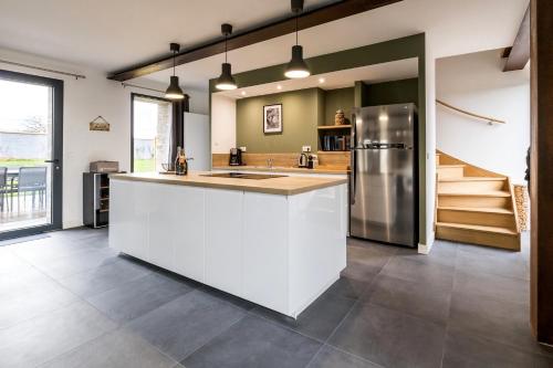 La cuisine est équipée d'un comptoir blanc et d'un réfrigérateur. dans l'établissement Large Bretonnerie, à La Haie-Fouassière