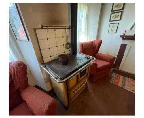 a small stove in a room with two chairs at Villa del Borgo in San Benedetto Val di Sambro