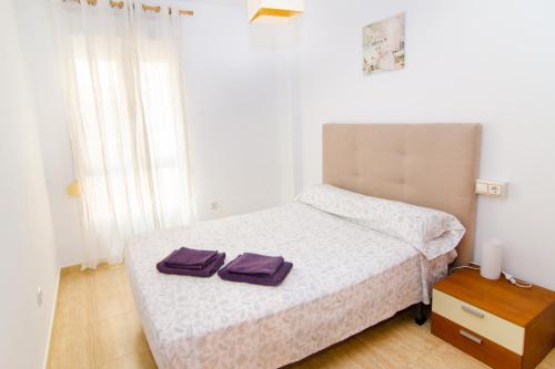 a bedroom with a bed with two purple towels on it at Apartamento de 4 dormitorios muy céntrico en San Juan Pueblo a tan sólo 2,5 km de la playa de San Juan y Muchavista in San Juan de Alicante