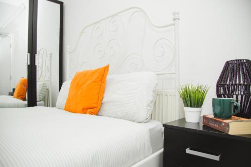 a bedroom with a white bed with an orange pillow at Modern Central Oasis in Liverpool