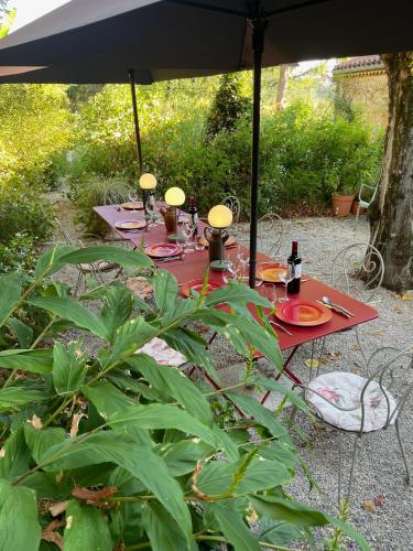 a table under an umbrella in a garden at La Dommerie-Gite de charme in Domme