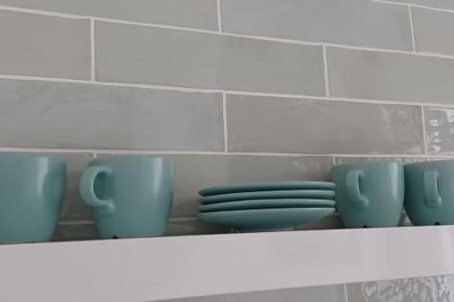 a shelf with blue cups and saucers on it at Un cocon les pieds dans l'eau in Le Moule