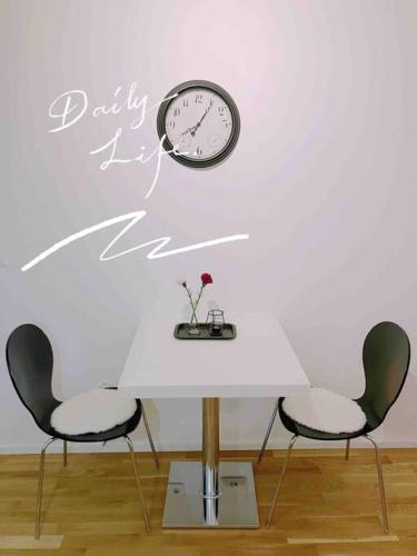 2 Stühle und ein Tisch mit einer Uhr an der Wand in der Unterkunft Central Apartment in Frankfurt a.M. in Frankfurt am Main