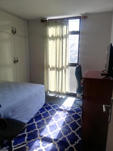 a bedroom with a bed and a desk and a window at Just a Room in Pretoria