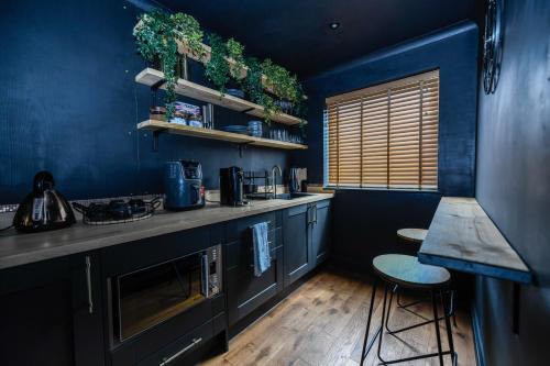 a kitchen with blue walls and a counter and stools at South coast boudoir in Bognor Regis