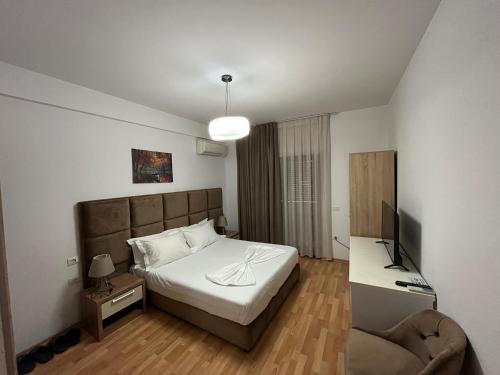 ein Schlafzimmer mit einem Bett, einem TV und einem Stuhl in der Unterkunft Rooms Dionis in Tirana